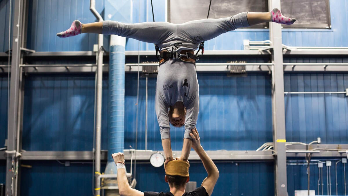 Une acrobate tente de maintenir son équilibre sur la tête de son partenaire.