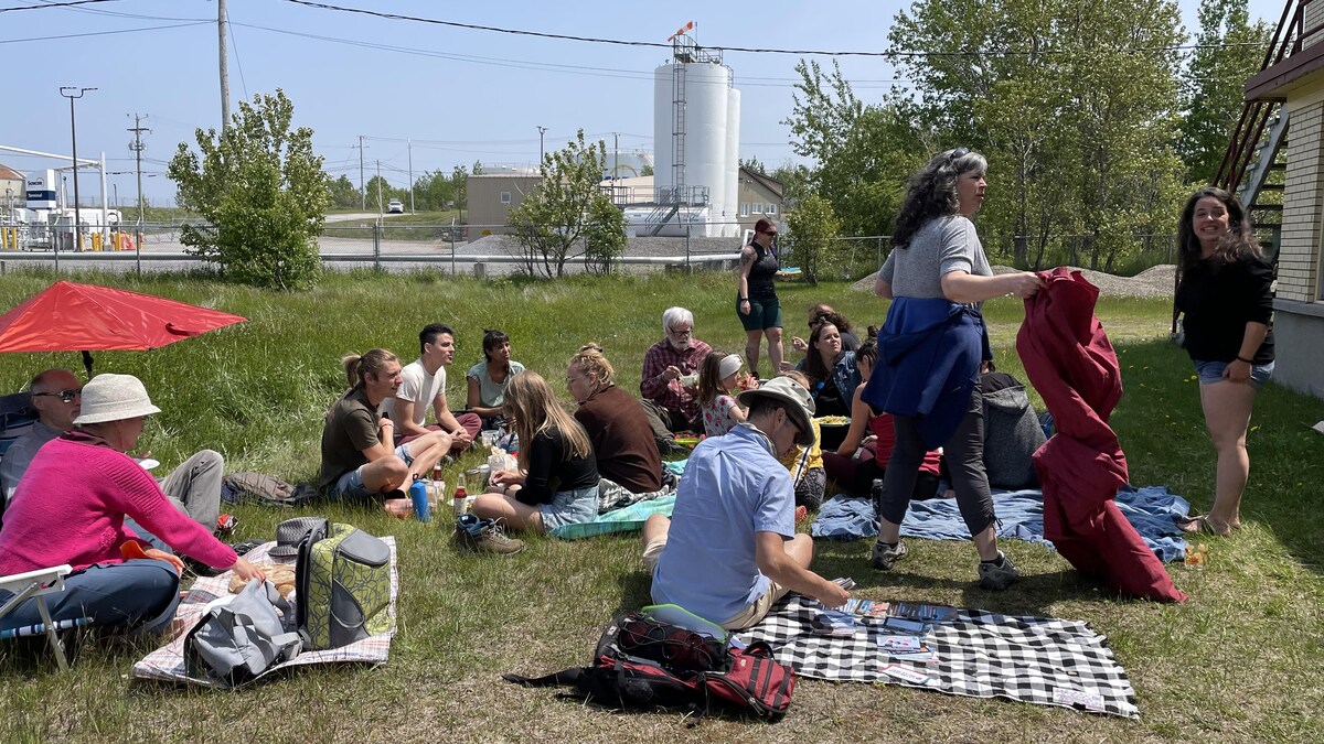 Des gens sont assis dans l'herbe à l'occasion d'un pique-nique.