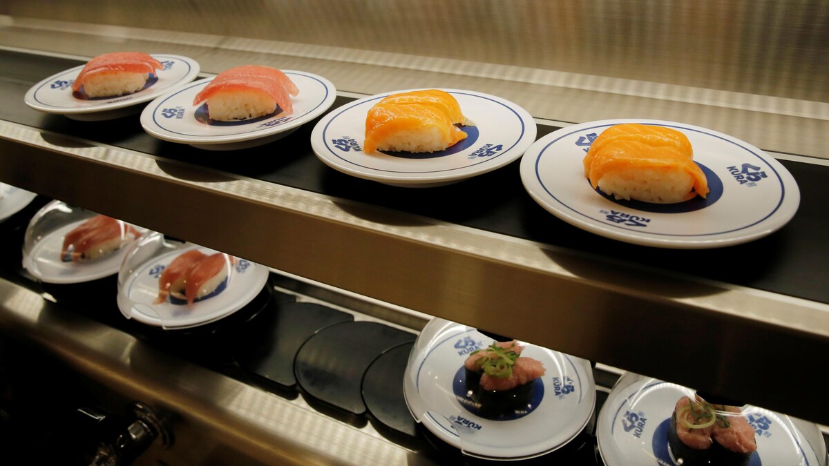 Une courroie de transport sur deux étages, sur laquelle sont posées des assiettes contenant du sushi.