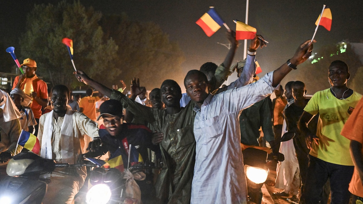 Des hommes fêtent une victoire électorale dans la rue en brandissant de petits drapeaux du Tchad.