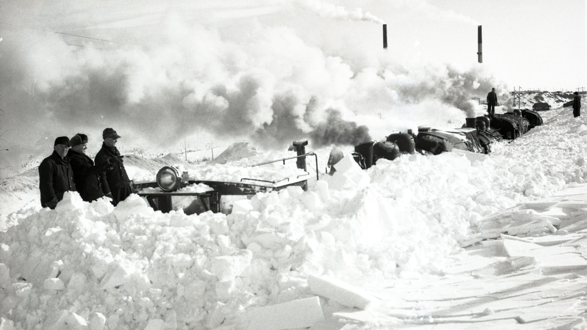 Un train enlisé dans la neige à Rouyn-Noranda lors de la grande tempête de 1947. En arrière plan, la mine Noranda.
