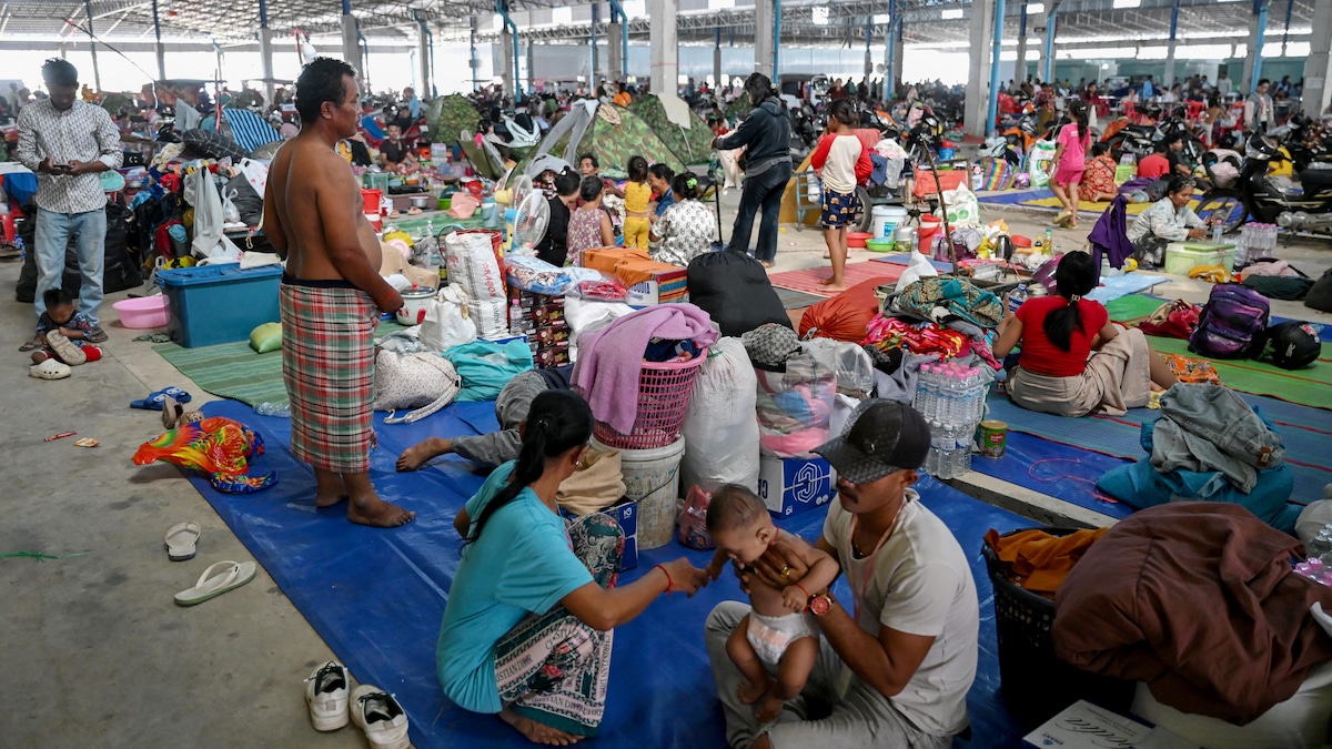 Des personnes assises au sol, avec leurs effets personnels.