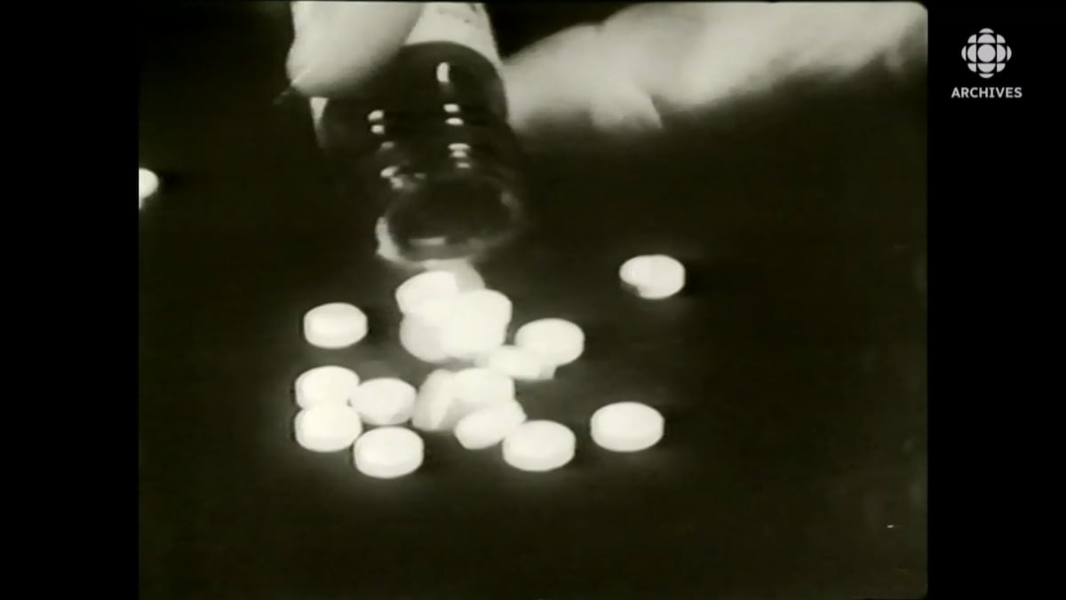 Plan rapproché d'une bouteille déversant des pilules blanches connues sous le nom de thalidomide.