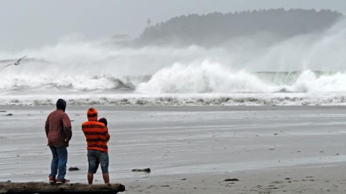 Un couple observe de grosses vagues se briser sur la plage Chesterman à Tofino en Colombie-Britannique