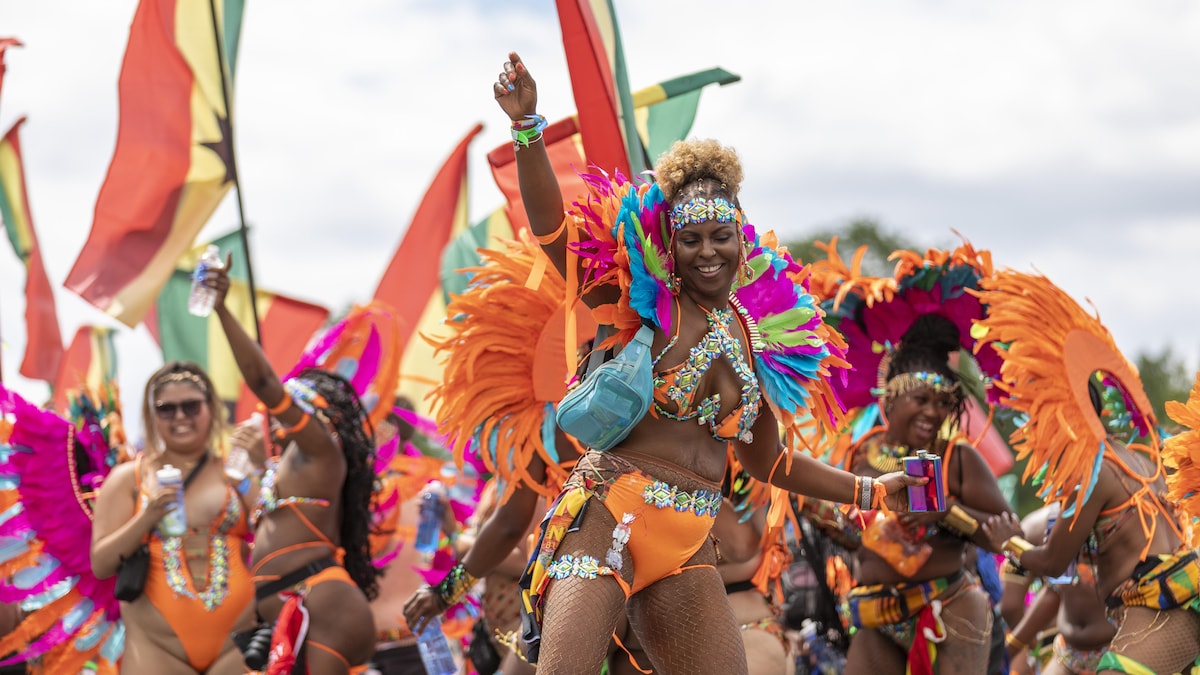 Des femmes portant des costumes confectionnés de plumes et de paillettes dansent lors du défilé carnavalesque à Toronto en 2022.