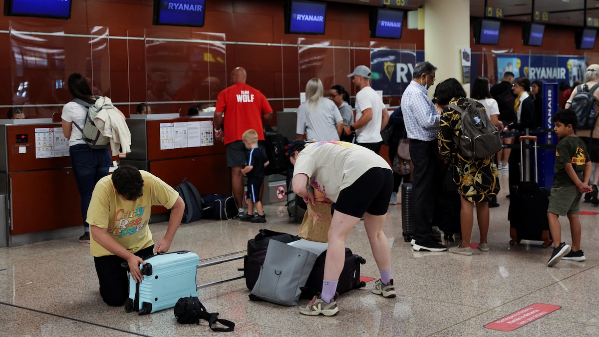 Deux personnes habillées comme de vrais touristes sont à genoux sur le plancher de l'aéroport, où ils ont éparpillé leurs effets personnels et ferment en vitesse leurs sacs et leurs valises.