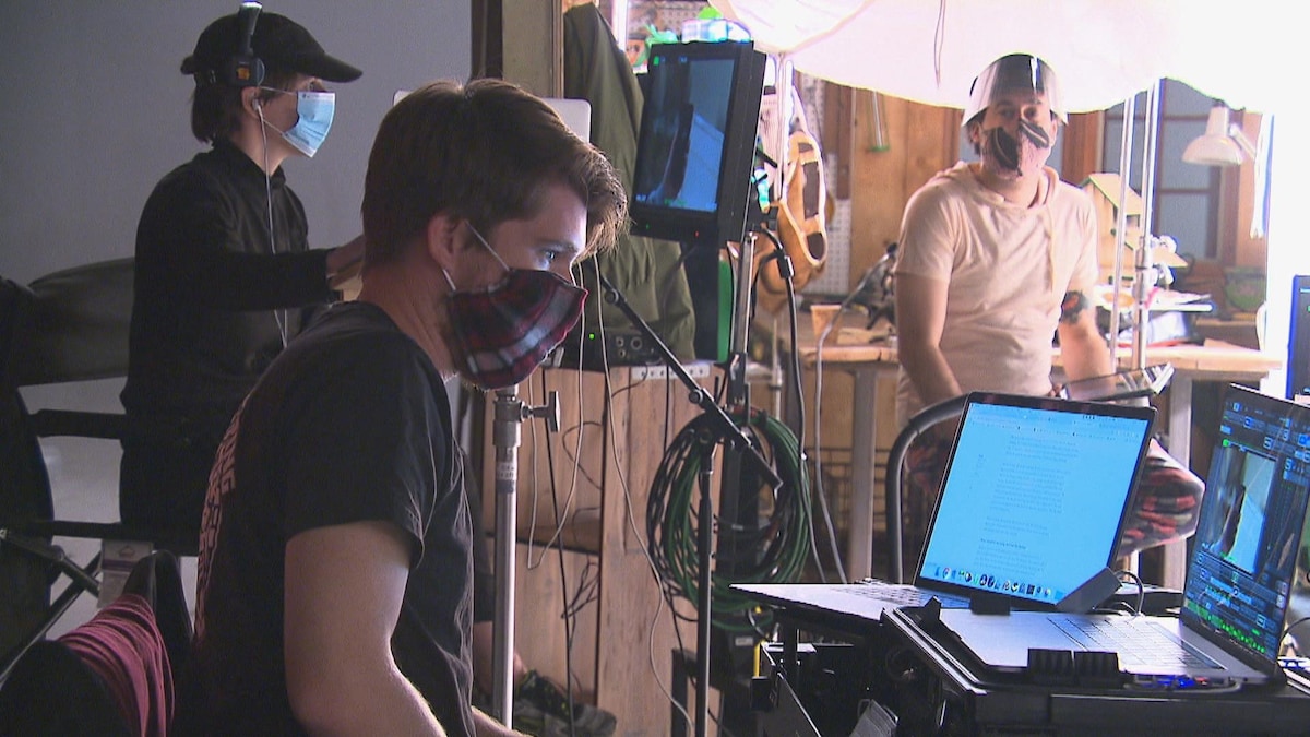 Trois personnes travaillent sur un plateau de tournage en portant un masque.