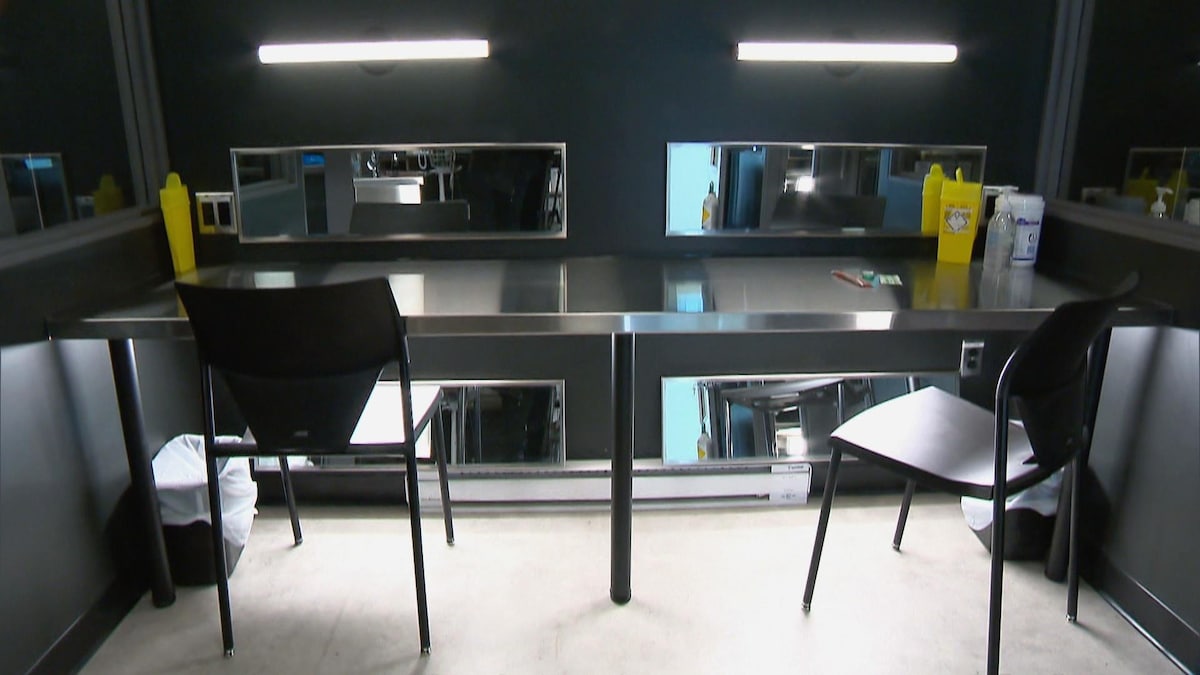 Une salle d'injection où sont disposés des seringues et des contenants à déchets sur une table stérile en aluminium.