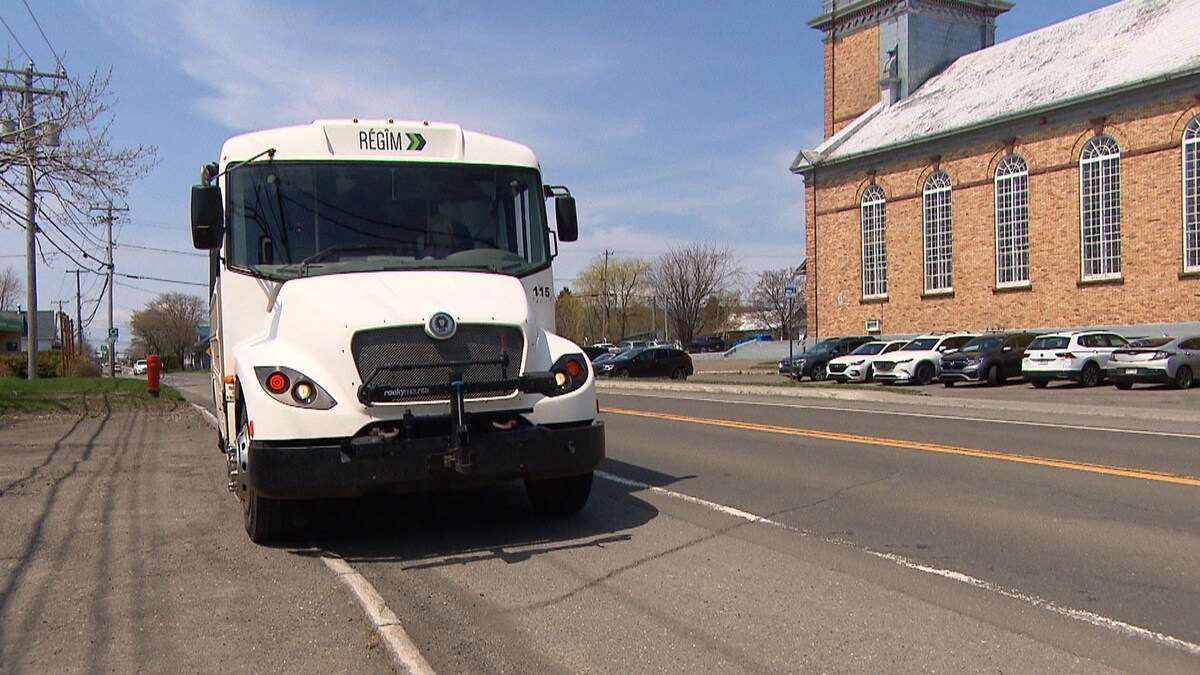 Un autobus blanc de petit format roule dans la rue à Carleton-sur-mer.