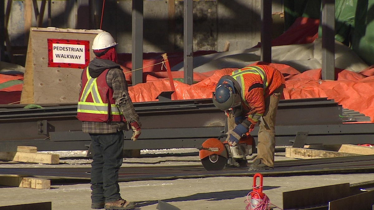 Deux travailleurs portant des vestes de sécurité sur un chantier de construction.