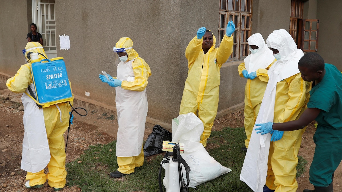 Des travailleurs de la santé ajustent leur équipement avant d'entrer dans une pièce où l'on soupçonne un bébé d'être mort d'Ebola en RDC.