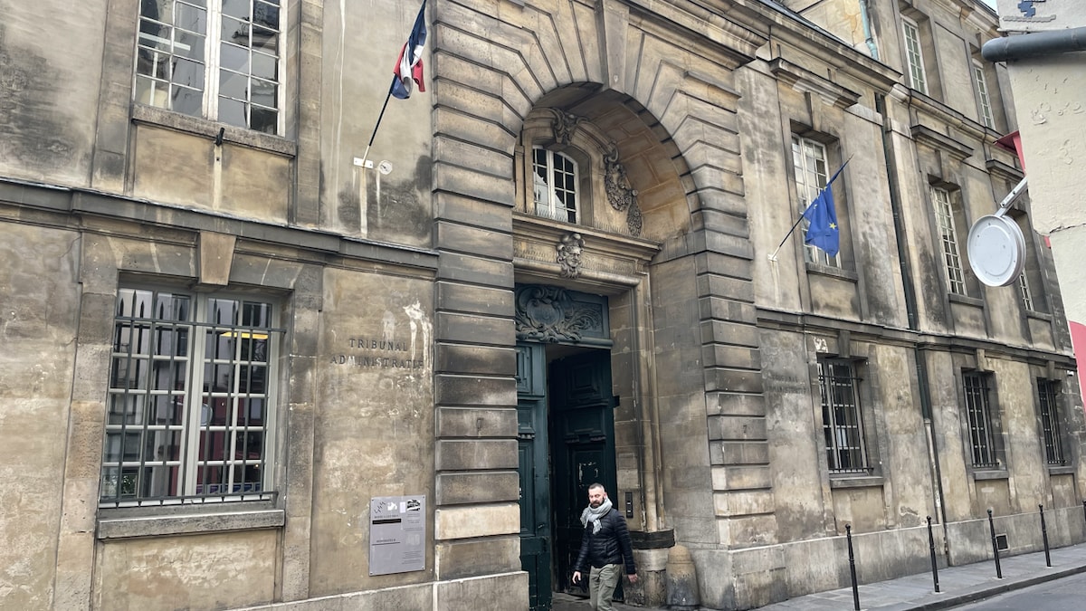 Un drapeau européen et un drapeau français sont disposés chaque côté de l'entrée du tribunal dans un immeuble historique.