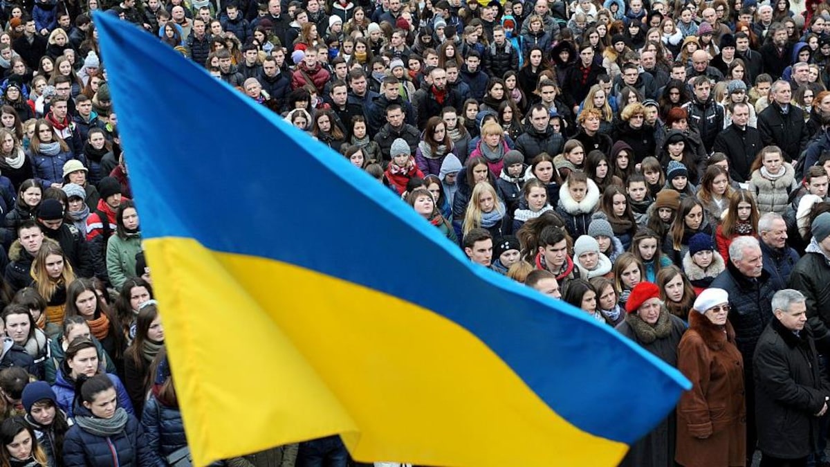 Une foule derrière le drapeau bleu et jaune de l'Ukraine.