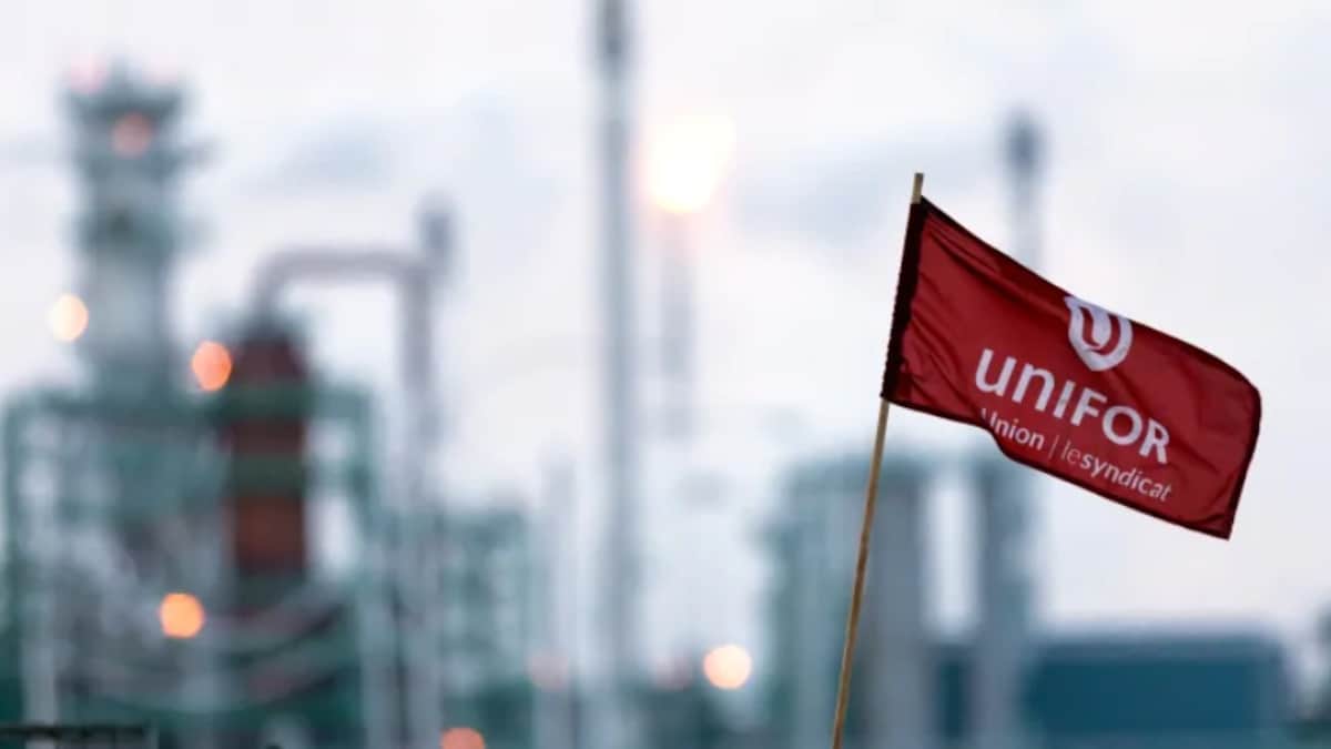 Un drapeau d'Unifor en avant-plan avec les installations de la raffinerie Co-op de Regina en arrière-plan.