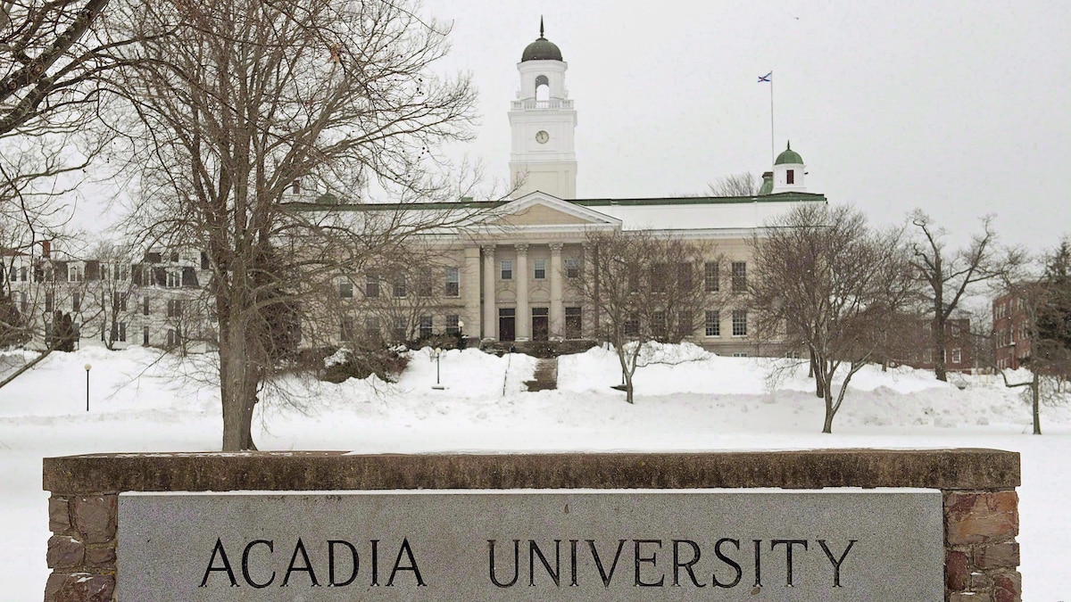 Bâtiment et enseigne de l'Université Acadia entourés de neige en hiver.