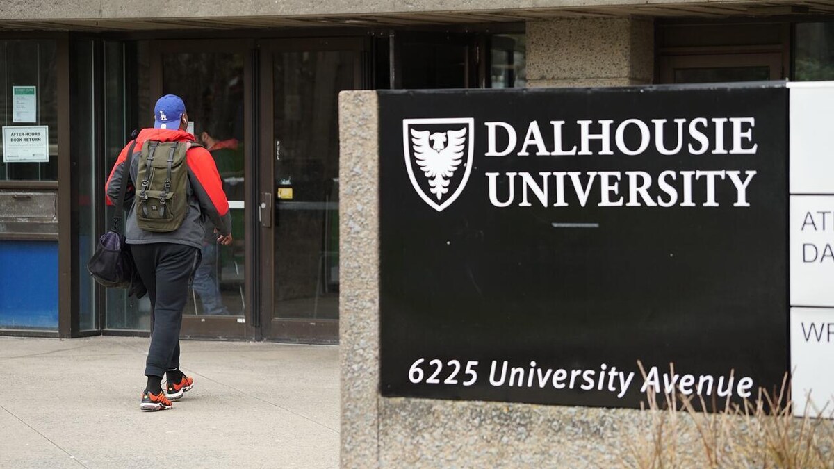 Une personne avec un sac à dos marche vers l'entrée de l'Université Dalhousie. 