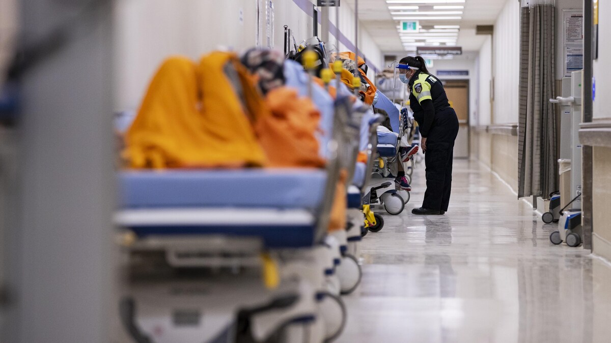 Une ambulancière parle à un patient sur une civière dans le corridor de l'urgence.