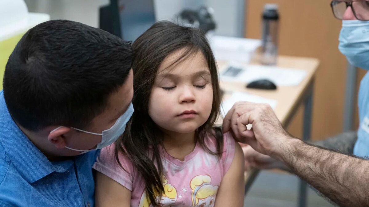 Une fillette accompagnée de son père est vaccinée.