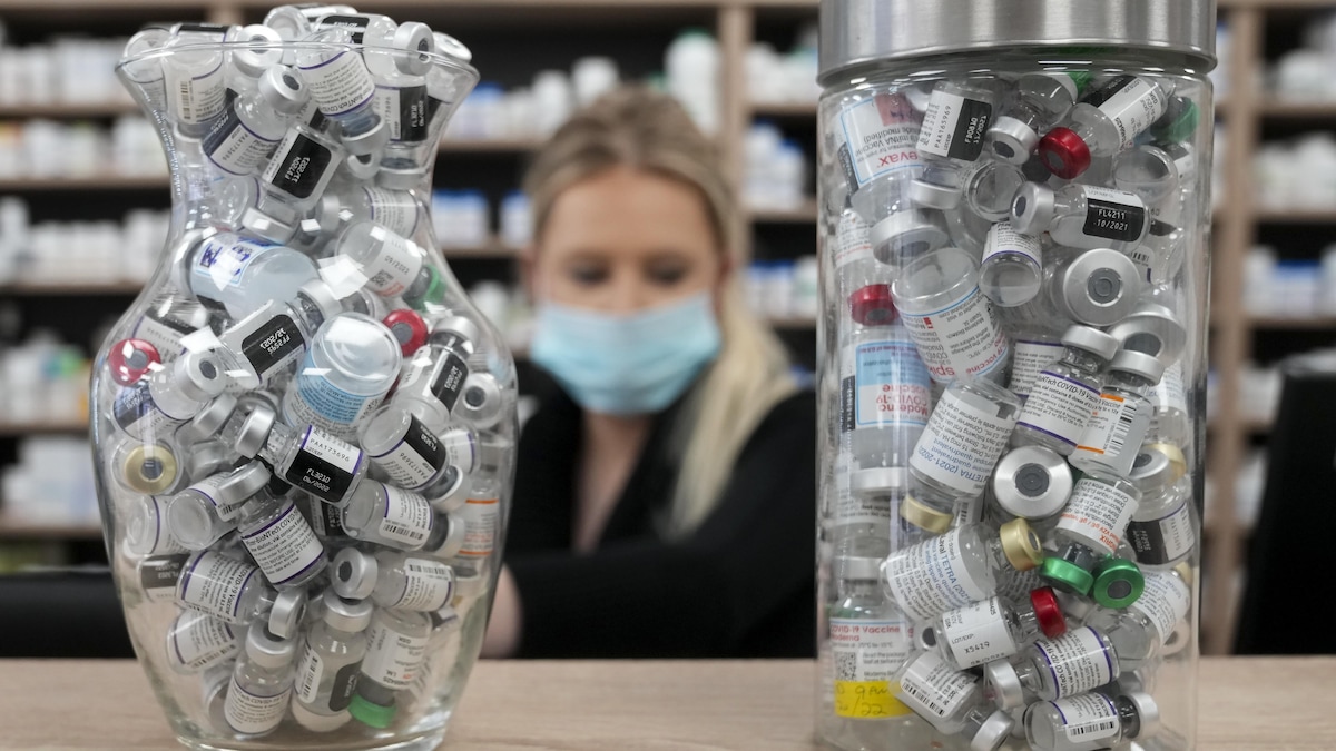 Deux contenants de verre remplis de fioles de vaccins sur le comptoir de la pharmacie.