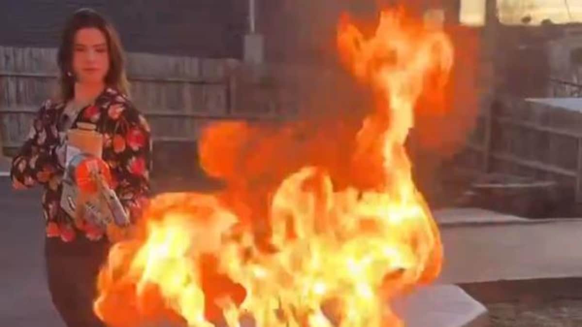 Une femme brûle deux livres au lance-flammes. 
