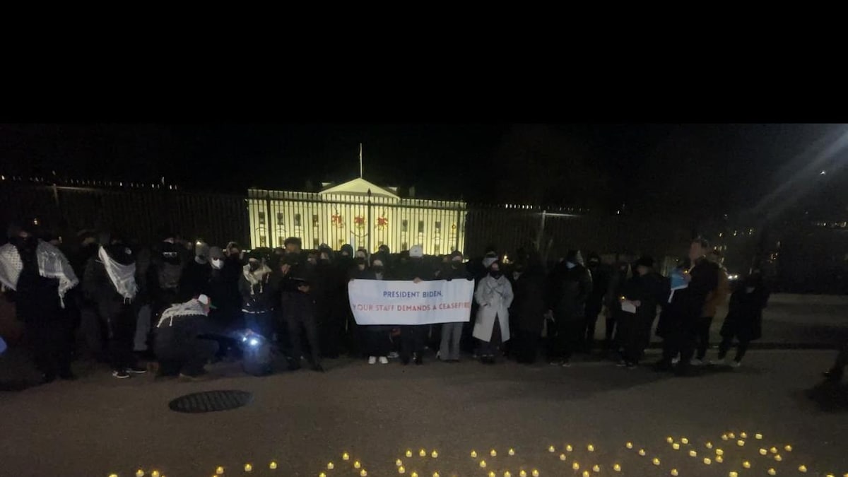 Une cinquantaine de personnes devant la Maison-Blanche tenant une banderole où il est inscrit : président Biden, vos employés demandent un cessez-le-feu.