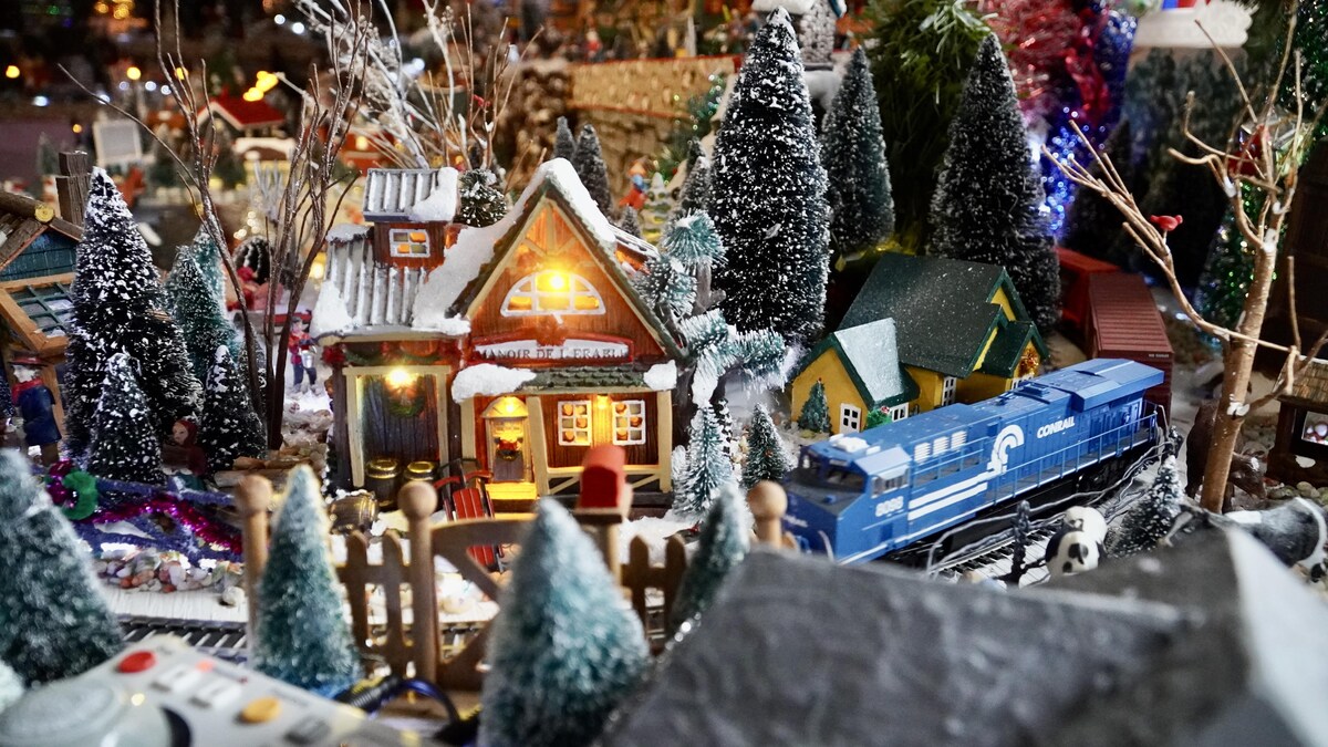 Une maisonnette et un train composent une partie du village miniature de Noël.                               