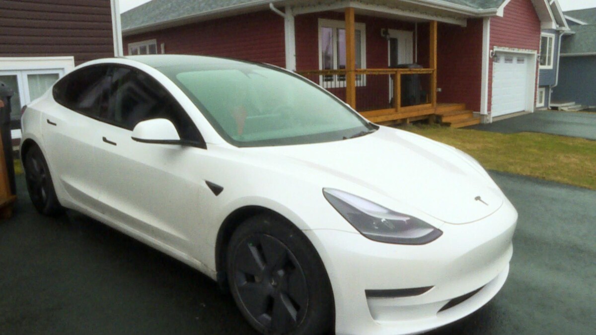 Une voiture Tesla garée devant une maison.