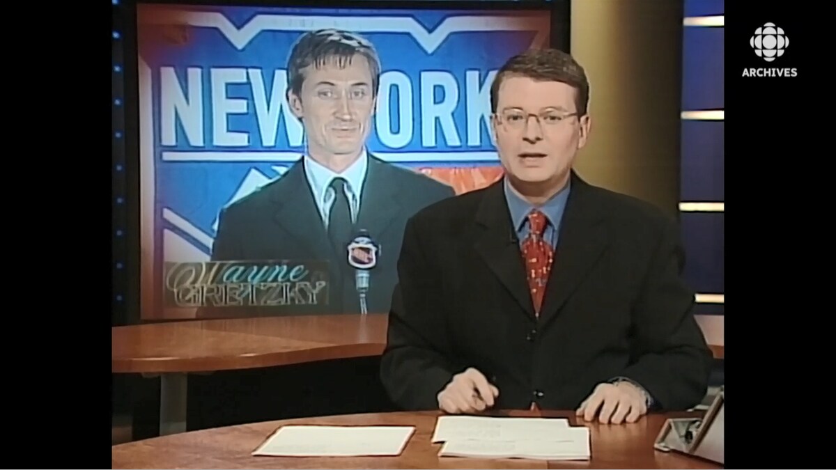 Stephan Bureau à son pupitre du Téléjournal devant une mortaise de la conférence de presse de Wayne Gretzky.