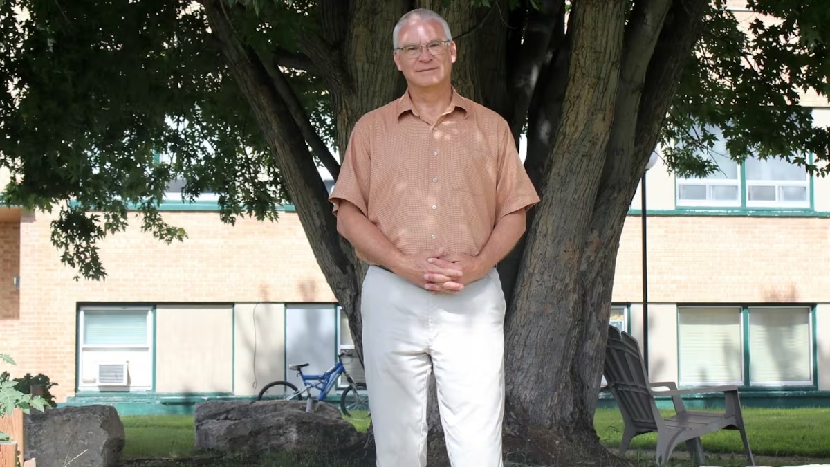 Wayne Olson est debout devant un arbre.
