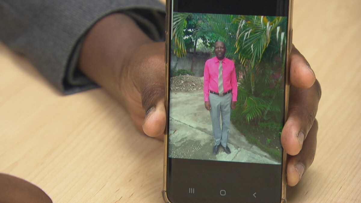 Un homme montre une photo de son frère sur son téléphone. 