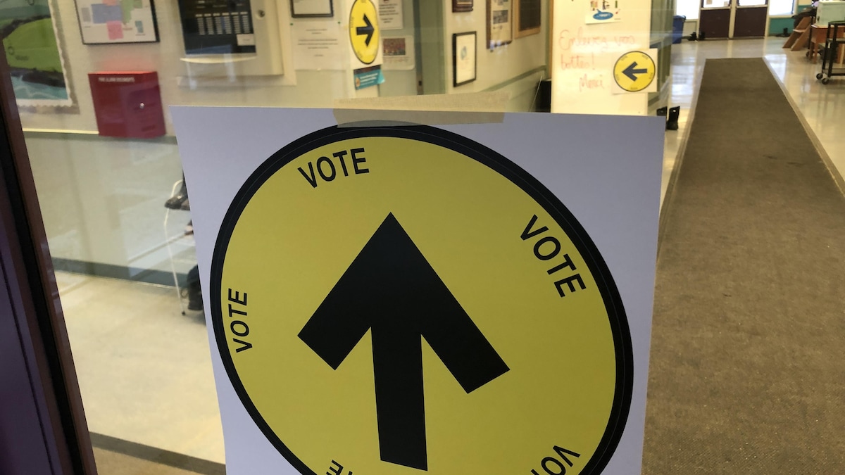 Une affiche indiquant un bureau de vote dans un couloir d'école.