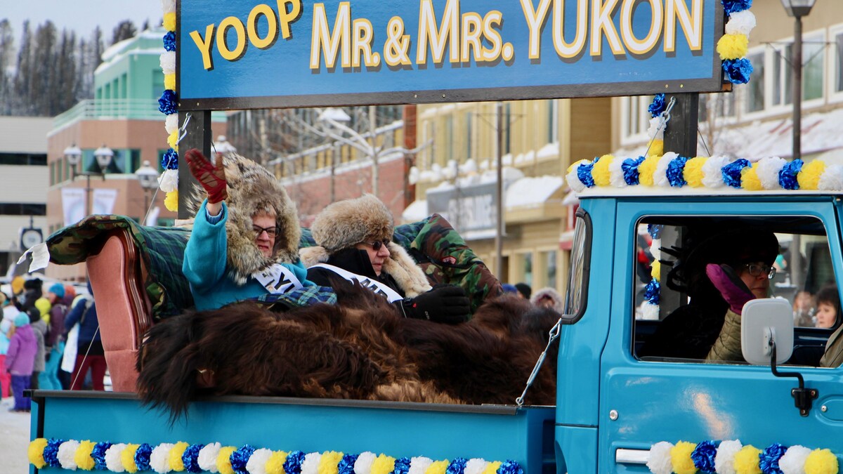 Une femme et un homme sont dans une camionnette. Ils saluent la foule.