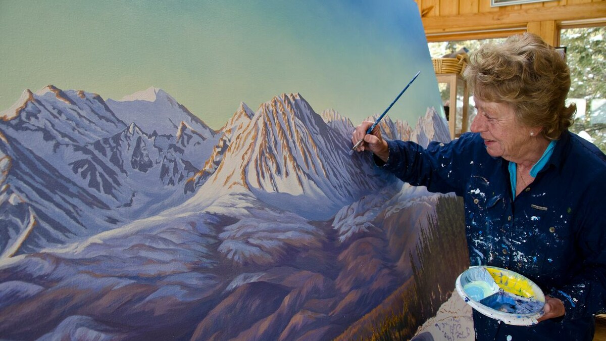 Libby Dulac devant l'une de ses toiles avec un pinceau. 