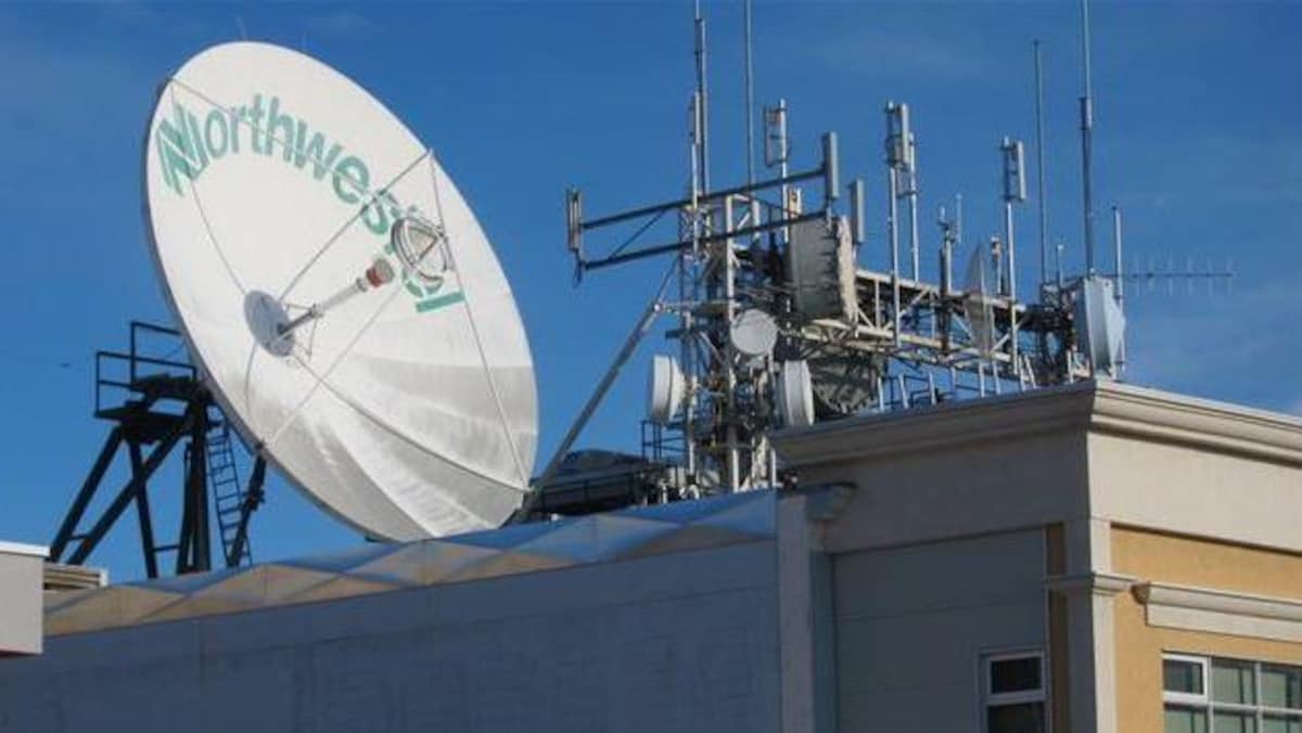 Une grande antenne ronde de télécommunications sur un toit avec le nom Northwestel inscrit dessus.