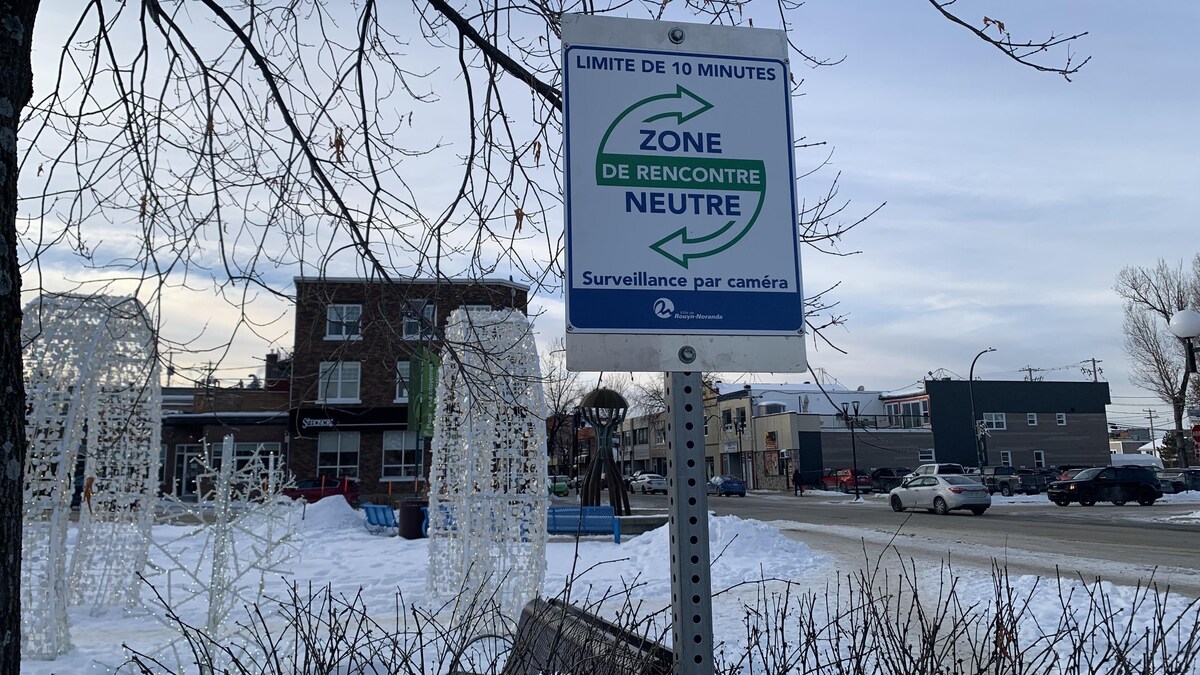 Un espace au centre-ville de Rouyn-Noranda, avec un petit indiquant Zone de rencontre neutre, limite de 10 minutes, Surveillance par caméra.