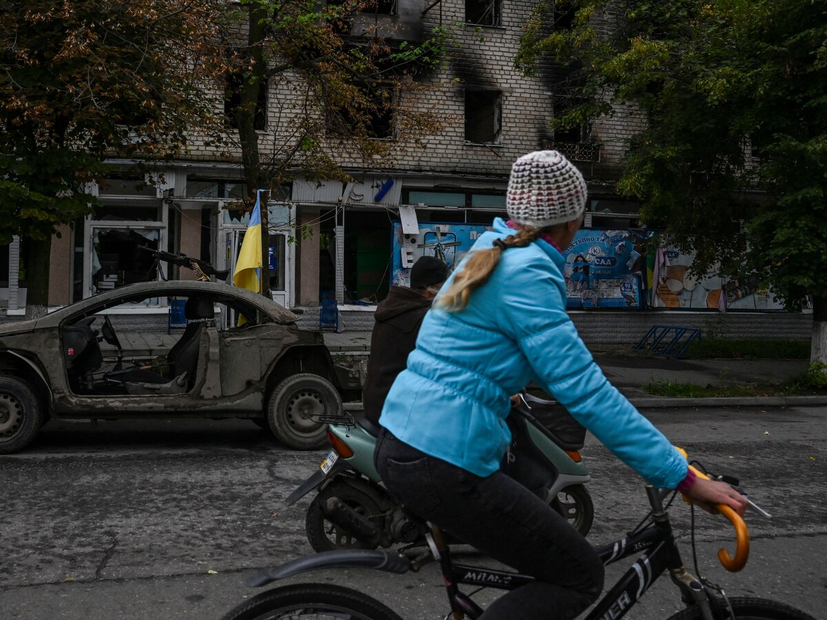 Une femme roule à vélo dans une rue d'Izioum, en Ukraine.