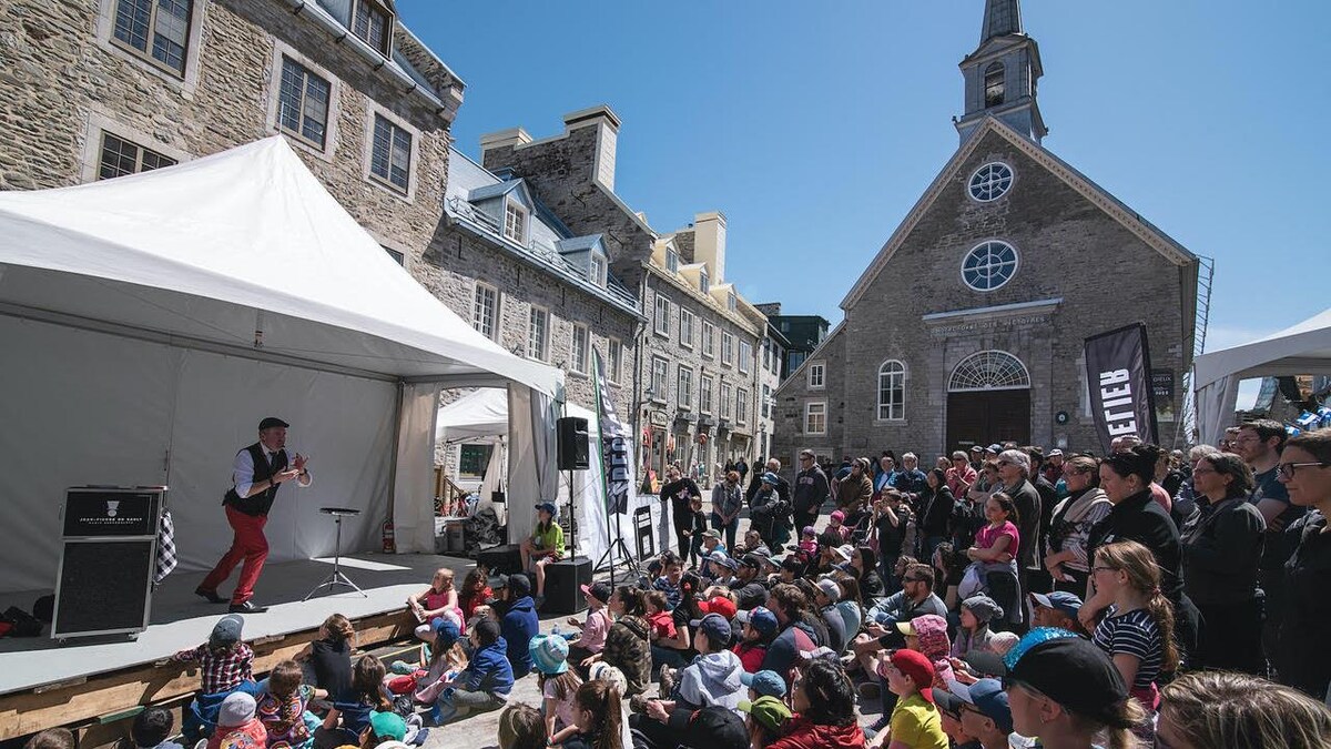 Magicien sur scène offrant un spectacle extérieur à la Place Royale à Québec lors d'une journée ensoleillée 