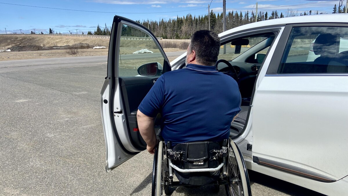 Une personne en situation de handicap s'apprête à rentrer dans sa voiture.