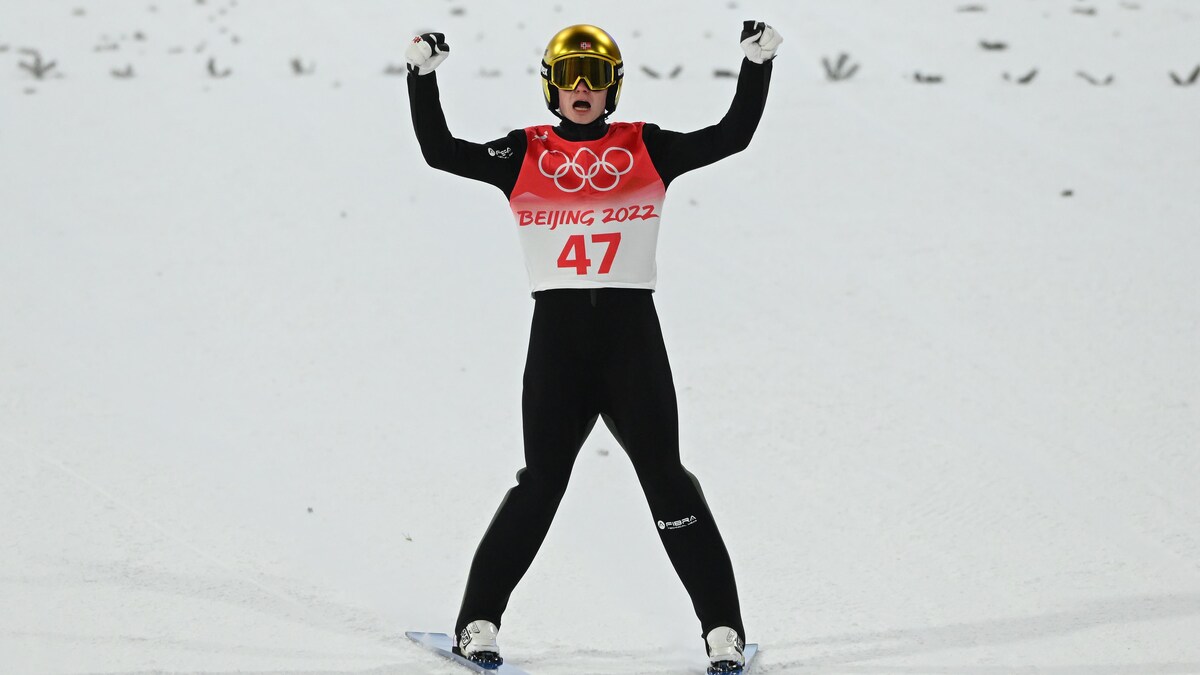 Le Norvégien Marius Lindvik lève les bras en célébration du saut à ski qu'il vient de réaliser.