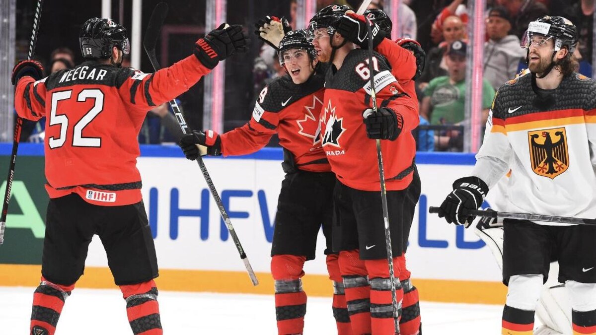 Trois joueurs de hockey du Canada se prennent dans les bras pour célébrer un but.