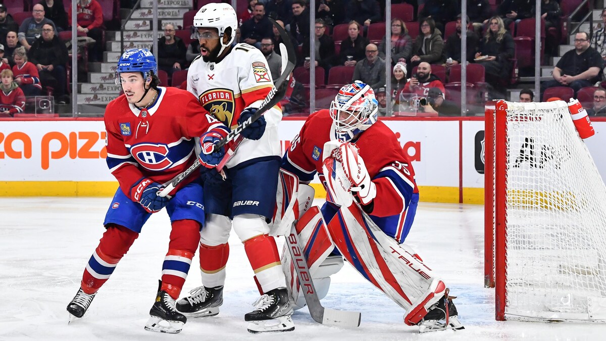 Deux joueurs de hockey se bousculent devant le gardien.