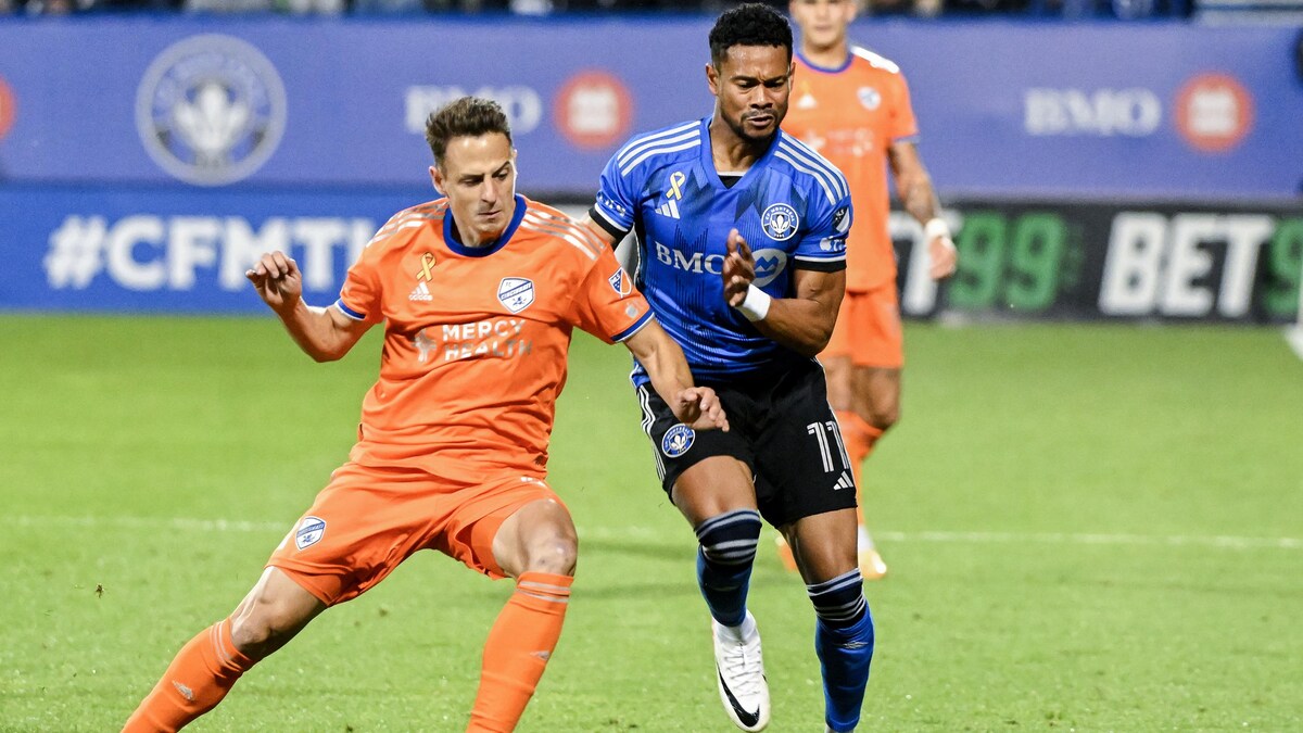 Deux joueurs de soccer d'équipes adverses se bataillent pour le ballon.