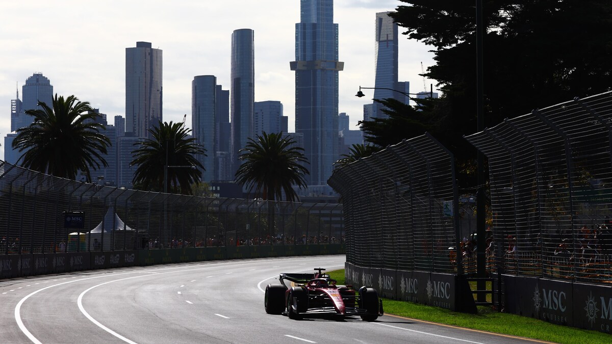 Une voiture de course en piste avec la ville de Melbourne en arrière plan.