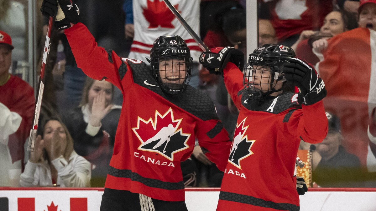 Deux joueuses de hockey lèvent les bras au ciel après avoir inscrit un but.