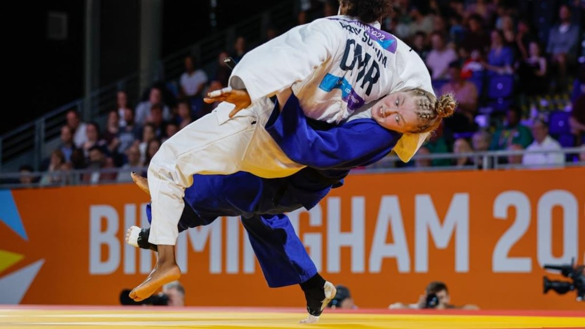 Pendant un combat de judo, une athlète saisit son adversire par la taille et tente de la retourner.