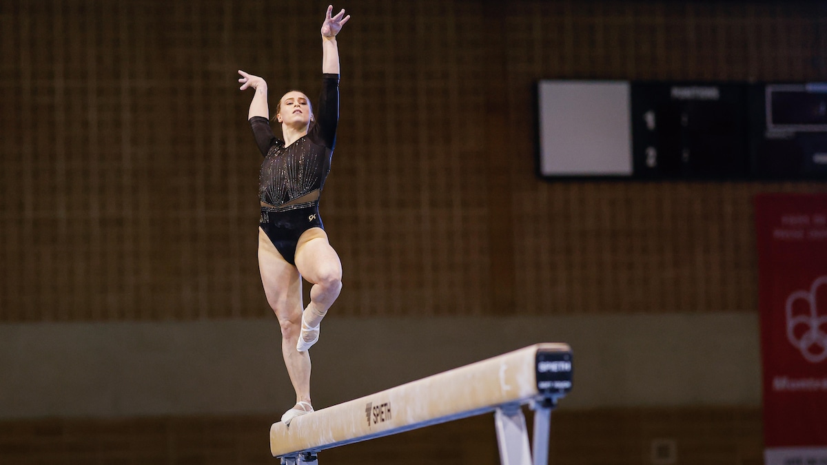 Une gymnaste se tient en équilibre sur une poutre.
