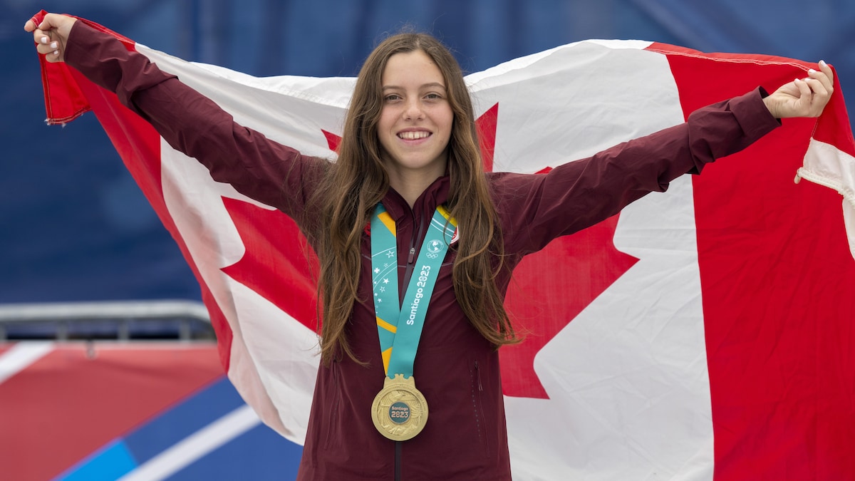 Souriante et avec une médaille d'or accrochée au cou, elle porte le drapeau canadien sur ses épaules. 