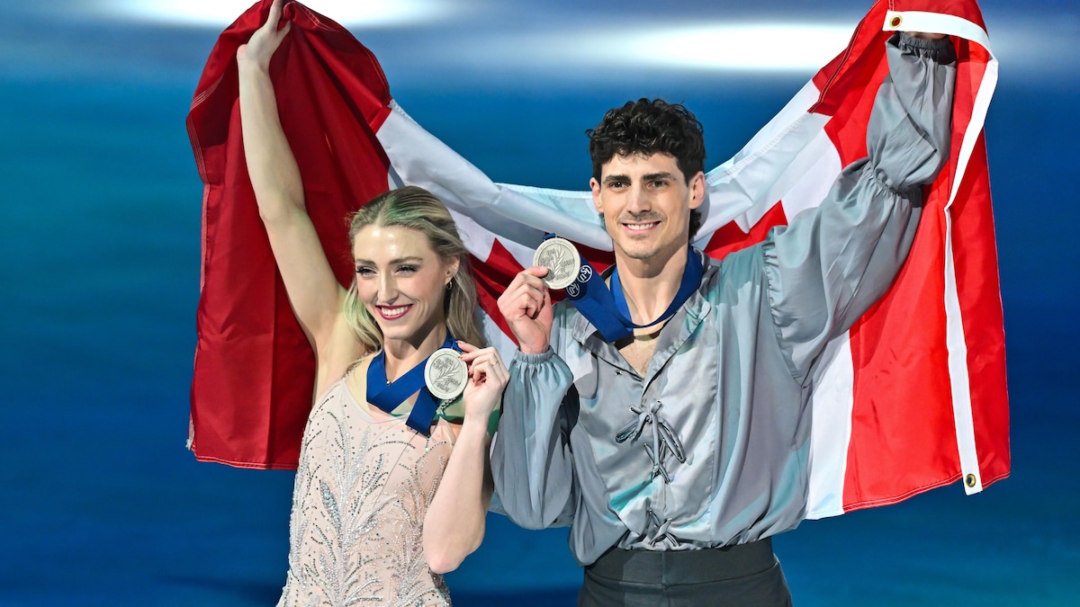 Deux athlètes montrent leur médailles d'argent et tiennent un drapeau canadien.