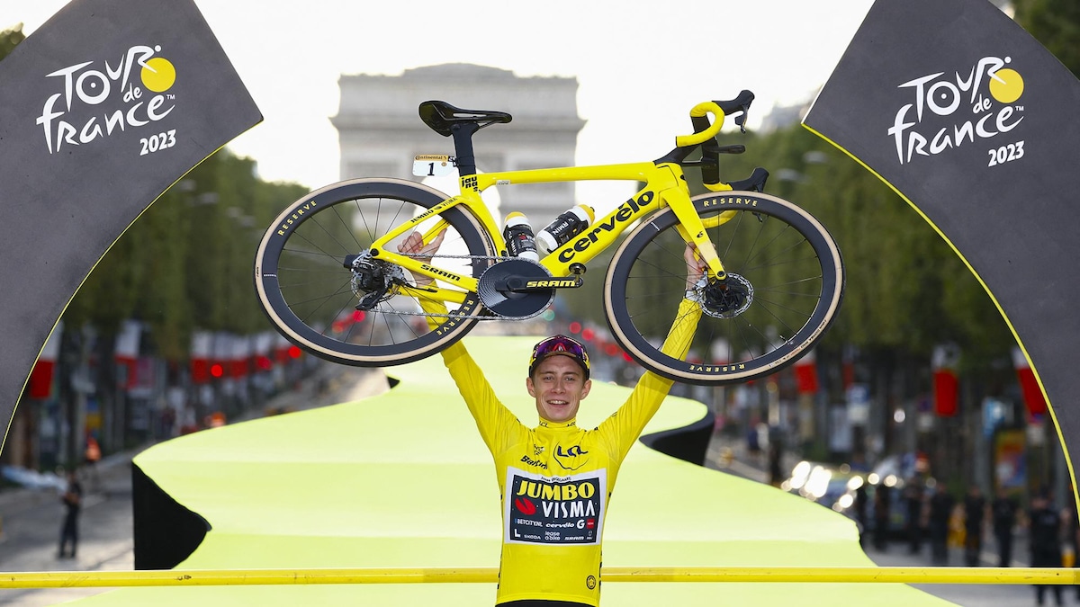 Il soulève son vélo sur les Champs-Élysées.