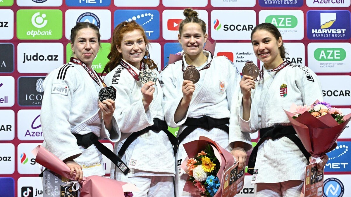 Avec les trois autres médaillées, elle montre sa médaille.